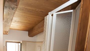 A bathroom with a wooden ceiling, a toilet, and a shower area.