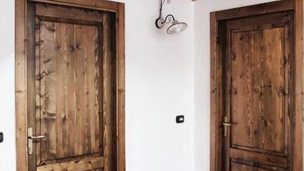 Un couloir avec des portes en bois et un sol carrelé.
