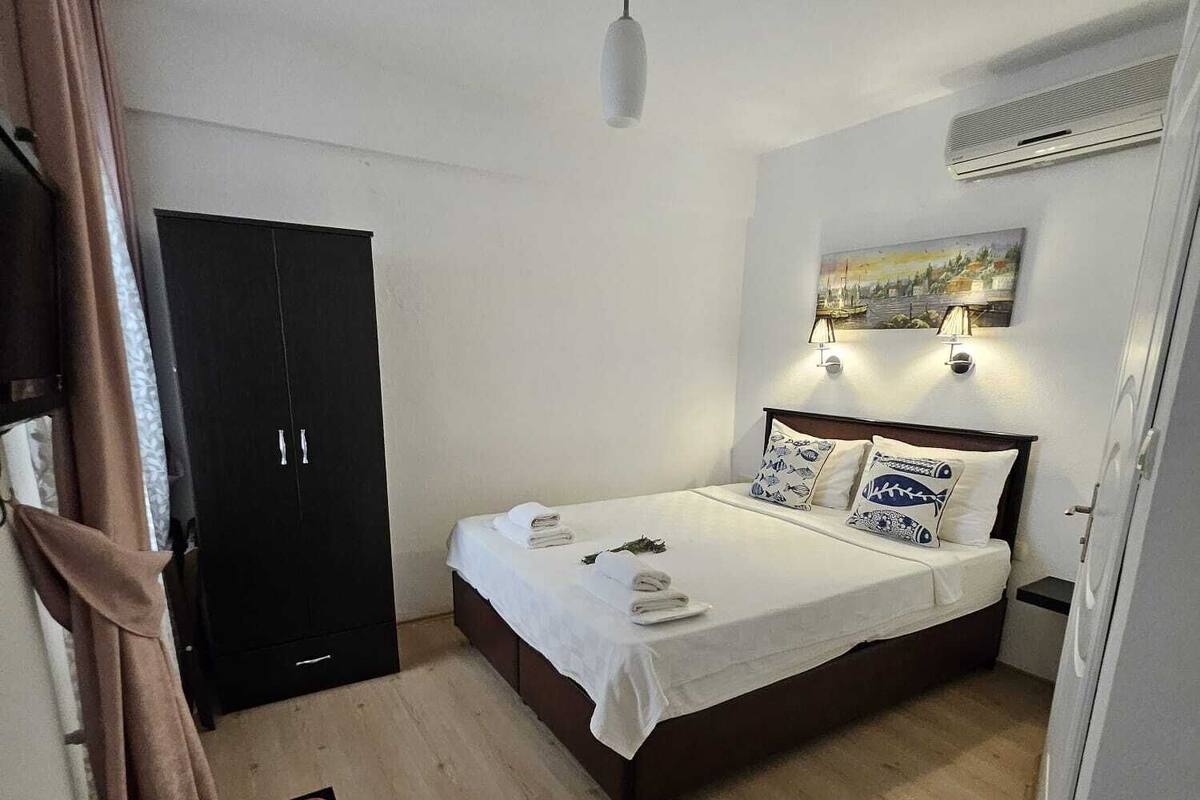 Un dormitorio con cama, armario, escritorio y un cuadro en la pared.