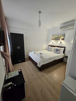 A bedroom with a bed, a wardrobe, a desk, and a painting on the wall. - Alize Otel (Bozcaada)