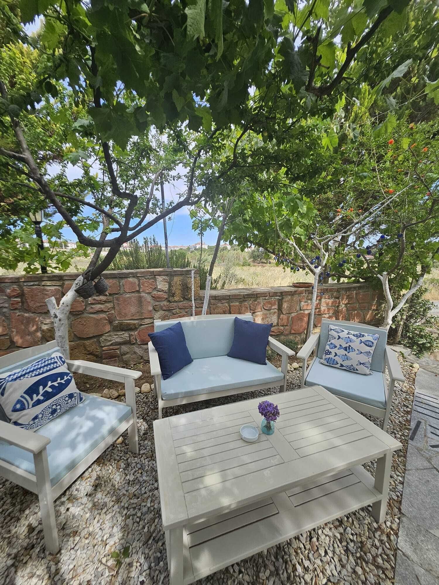 An outdoor seating area with a stone wall, a white table, and blue-patterned cushions.