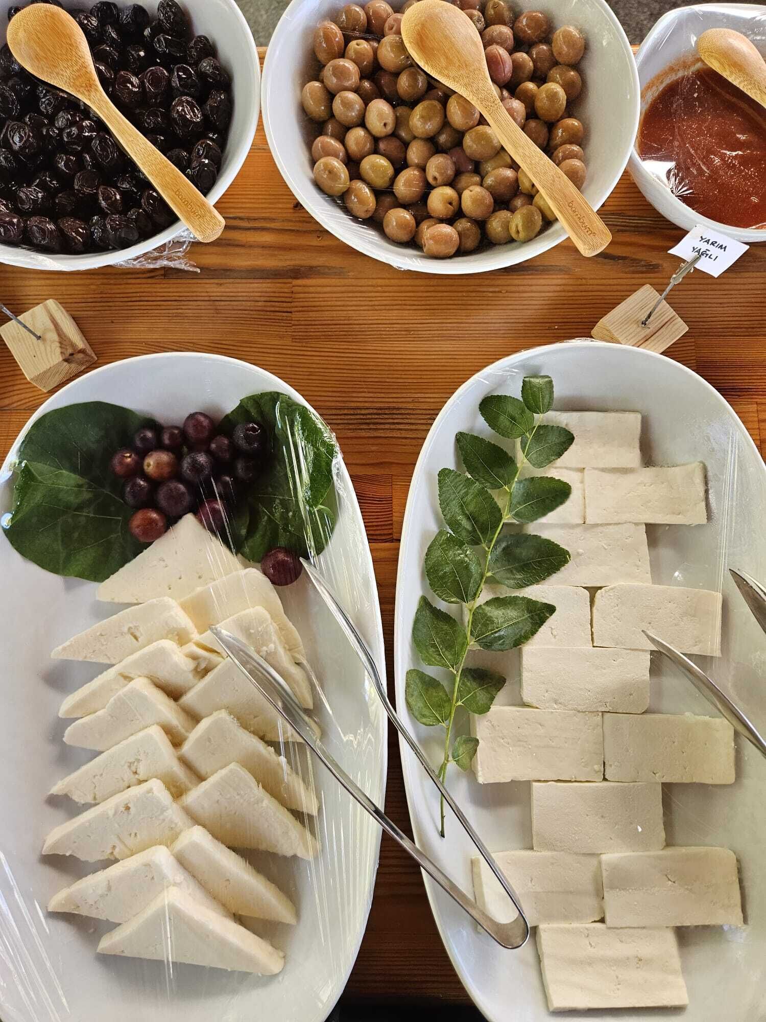 Een tafel met verschillende soorten eten, zoals plakjes kaas, druiven en ander fruit.