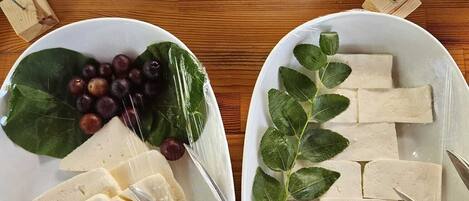 Een tafel met verschillende soorten eten, zoals plakjes kaas, druiven en ander fruit.