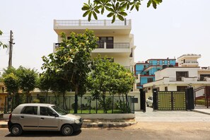 A multi-story residential building with a gated entrance and a parked car in front. - OYO 595 Hotel Aravali View (Gurugram)