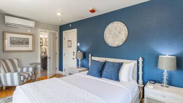 Une chambre à coucher avec un grand lit, une chaise, une table de chevet avec une lampe et une assiette décorative accrochée au mur.