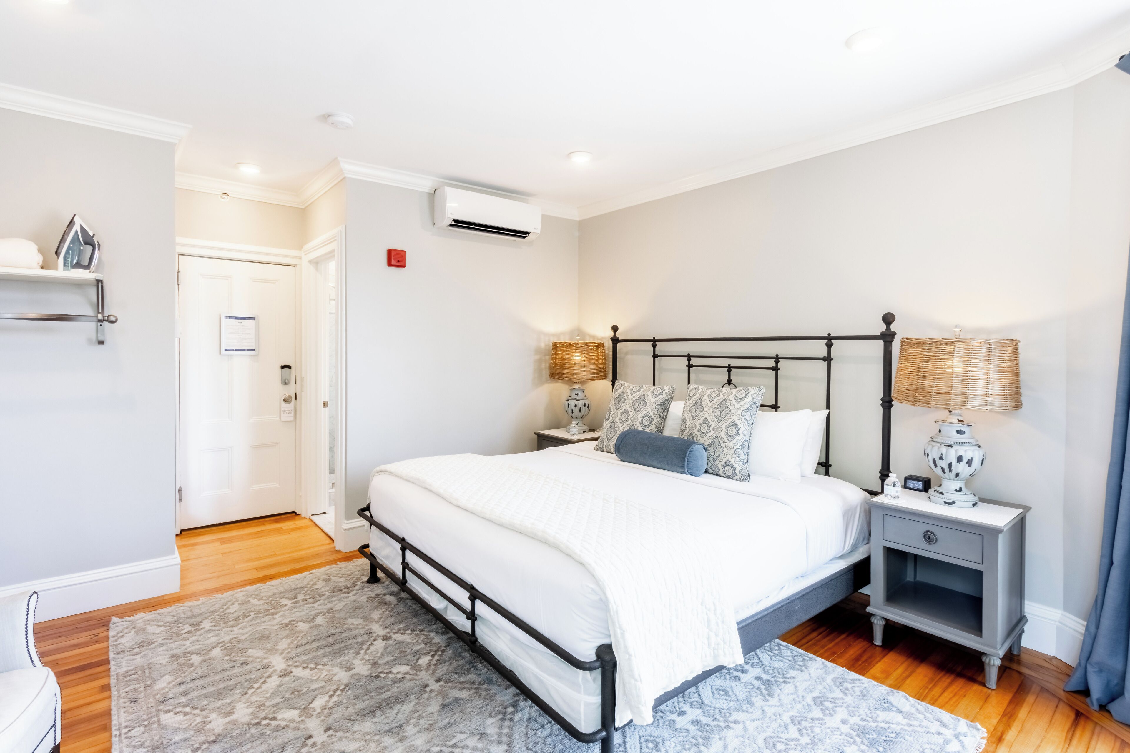 Un dormitorio con cama, mesitas de noche, lámpara y puerta.