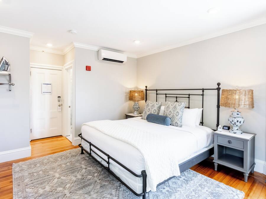 Un dormitorio con cama, mesitas de noche, lámpara y puerta.