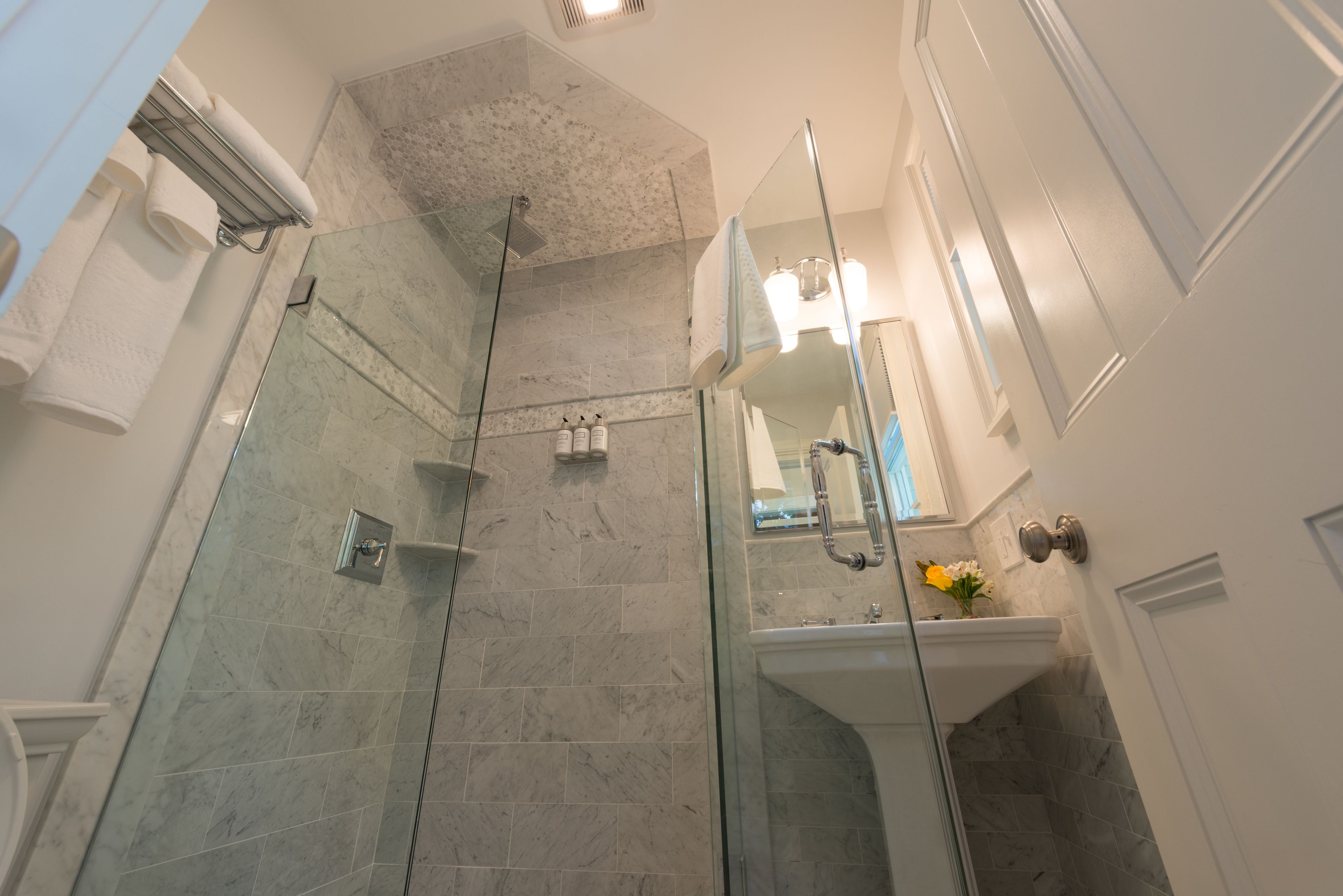 A modern bathroom with a glass-enclosed shower, a white sink, and a mirror above it.