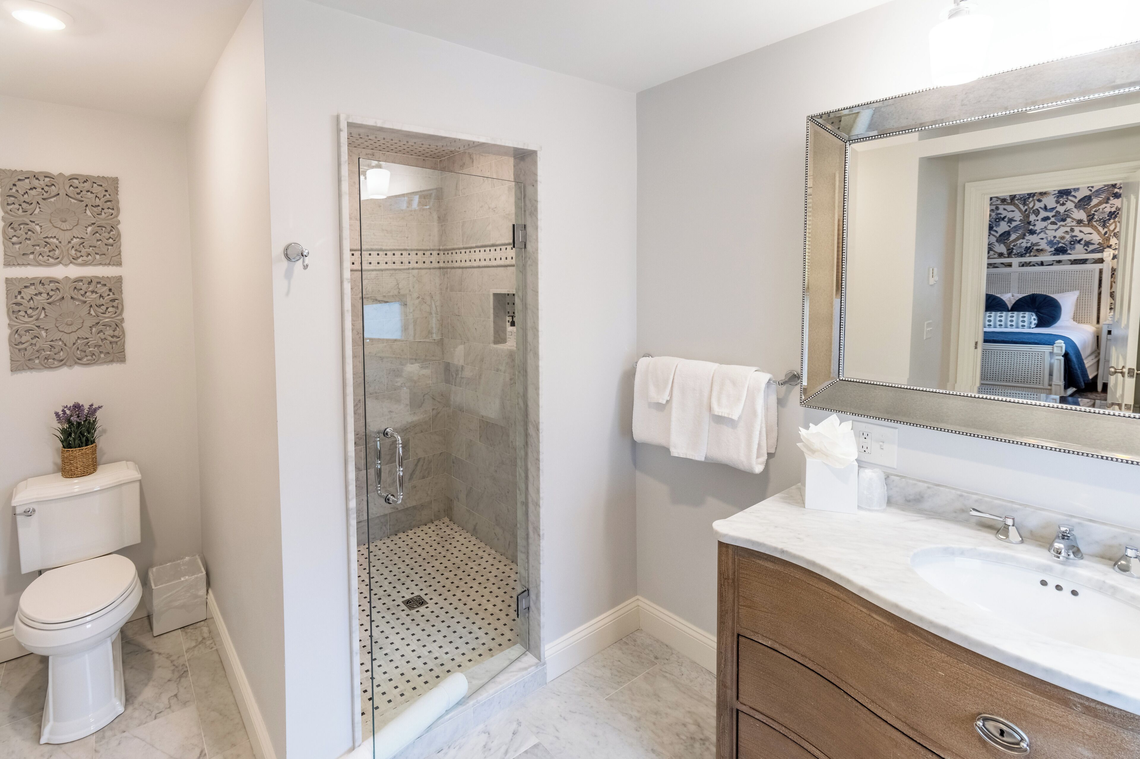 Un bagno moderno con doccia vetrata, un water bianco, un lavabo in marmo e uno specchio grande.