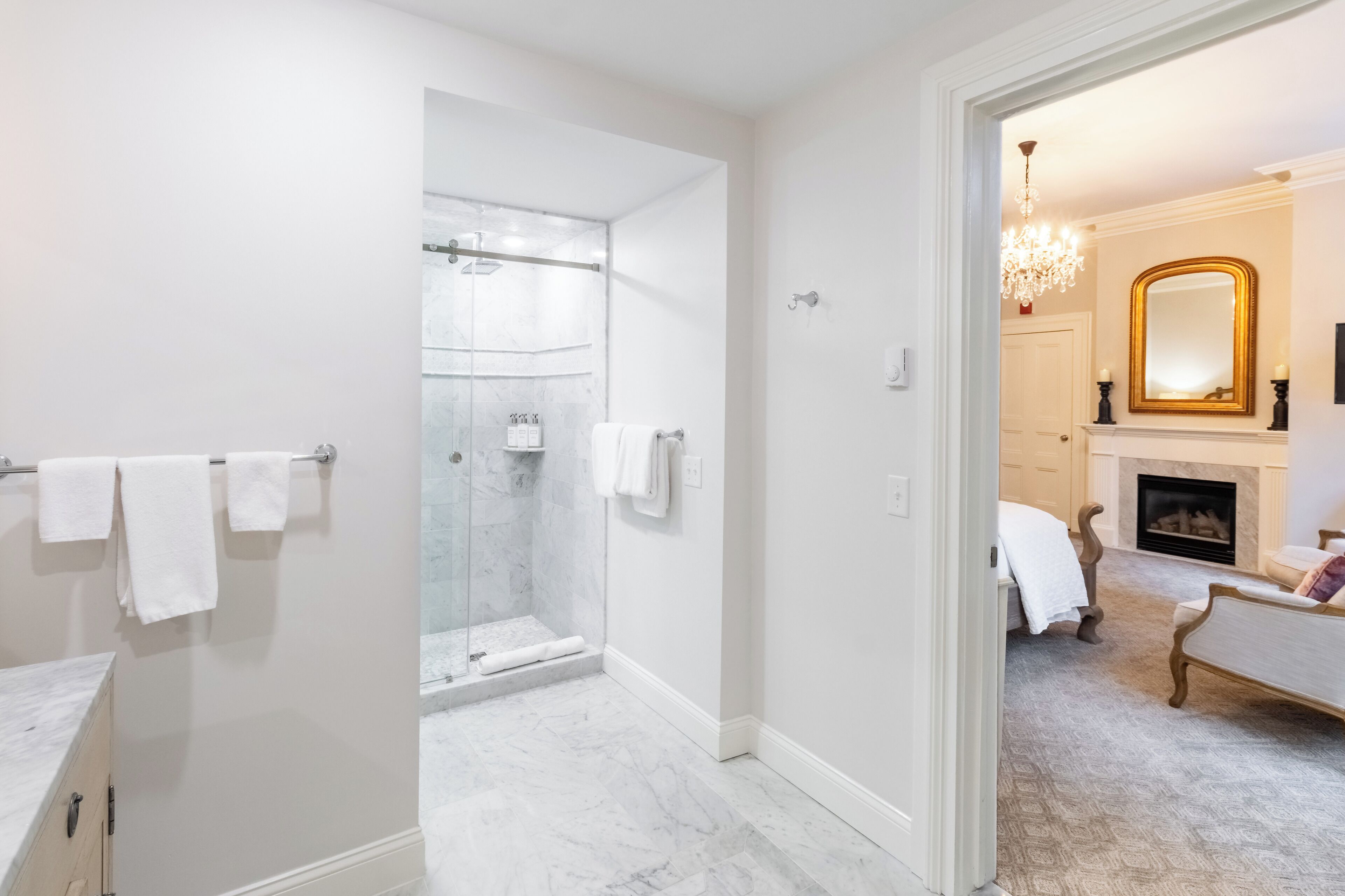 Un baño moderno con cabina de ducha de vidrio, suelo de mármol y tocador blanco.