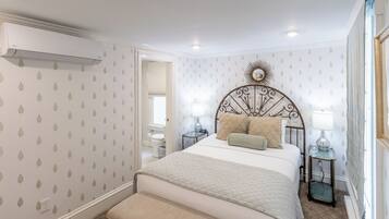 A bedroom with a bed, bedside tables, a nightstand, a mirror, and a window.
