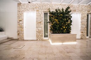 A spacious lobby with a stone wall, two white doors, and a planter with green foliage and yellow flowers.