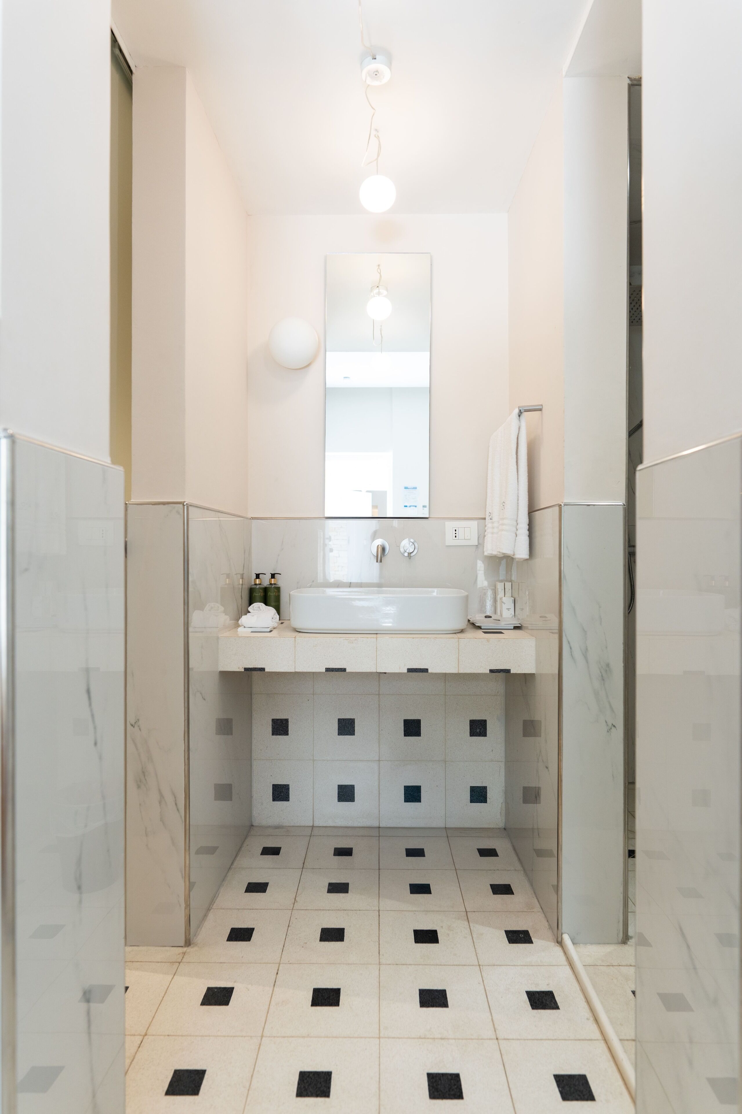 A bathroom with a white sink, mirror, and tiled floor.