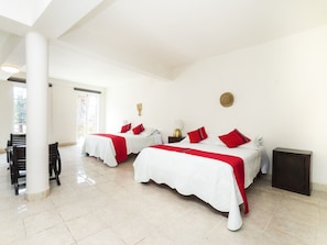Quarto de hotel com duas camas, área de refeições e vista para o exterior.