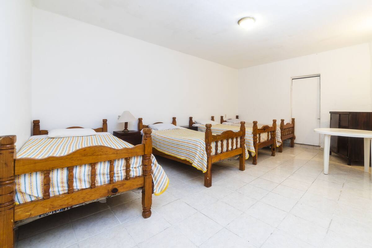 Ein Zimmer mit vier Holzbett, einem weißen Tisch und einer Tür.