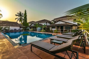 A swimming pool with lounge chairs and a 'POOL CLOSED' sign, surrounded by houses and palm trees. - Silver Sands Holiday Village (Candolim)