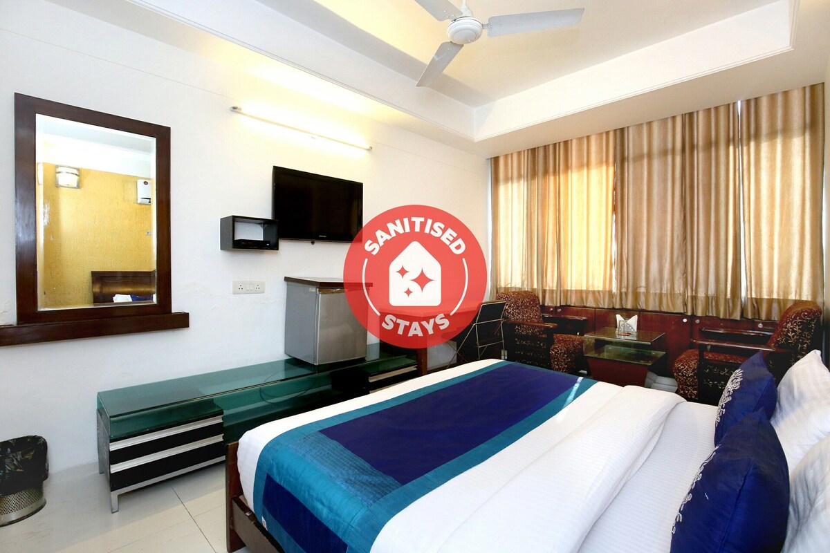 A hotel room with a bed, a desk, a television, and a mirror.