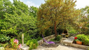 Un jardin avec un banc en pierre, une petite table et une chaise.