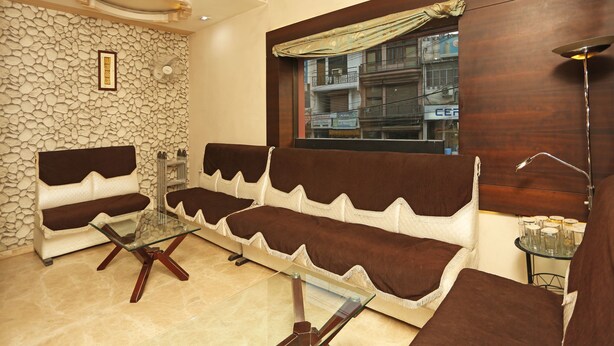 A modern living room with a stone wall, a glass coffee table, and a sofa set. - OYO 1671 Hotel Sundaram (Prayagraj)