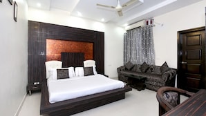 A modern bedroom with a bed, a sofa, and a dining table. - Capital O 9235 Hotel Nayyar (Amritsar)