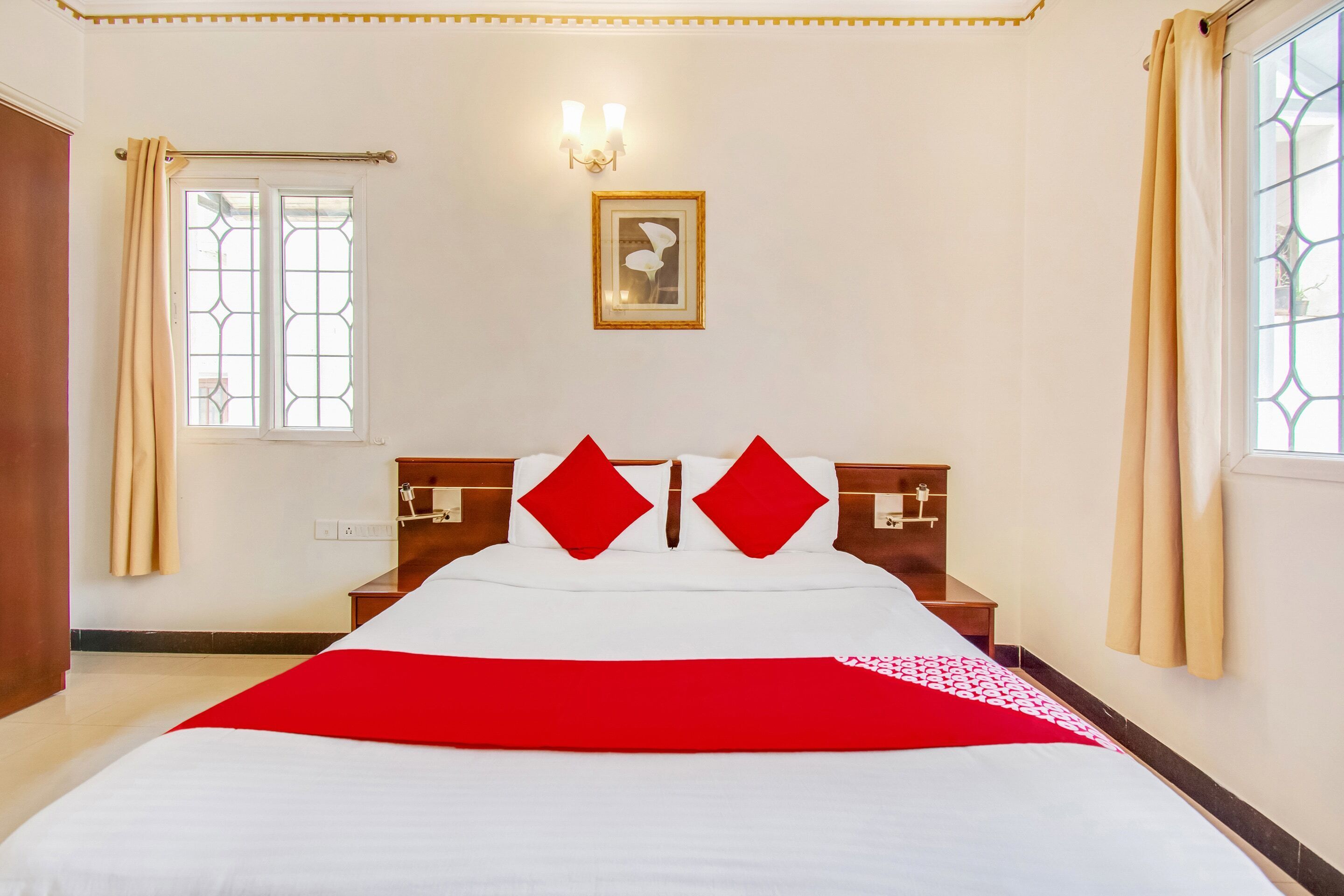 Habitación de hotel con una cama grande, dos mesitas de noche, un cuadro en la pared y una ventana con cortinas.