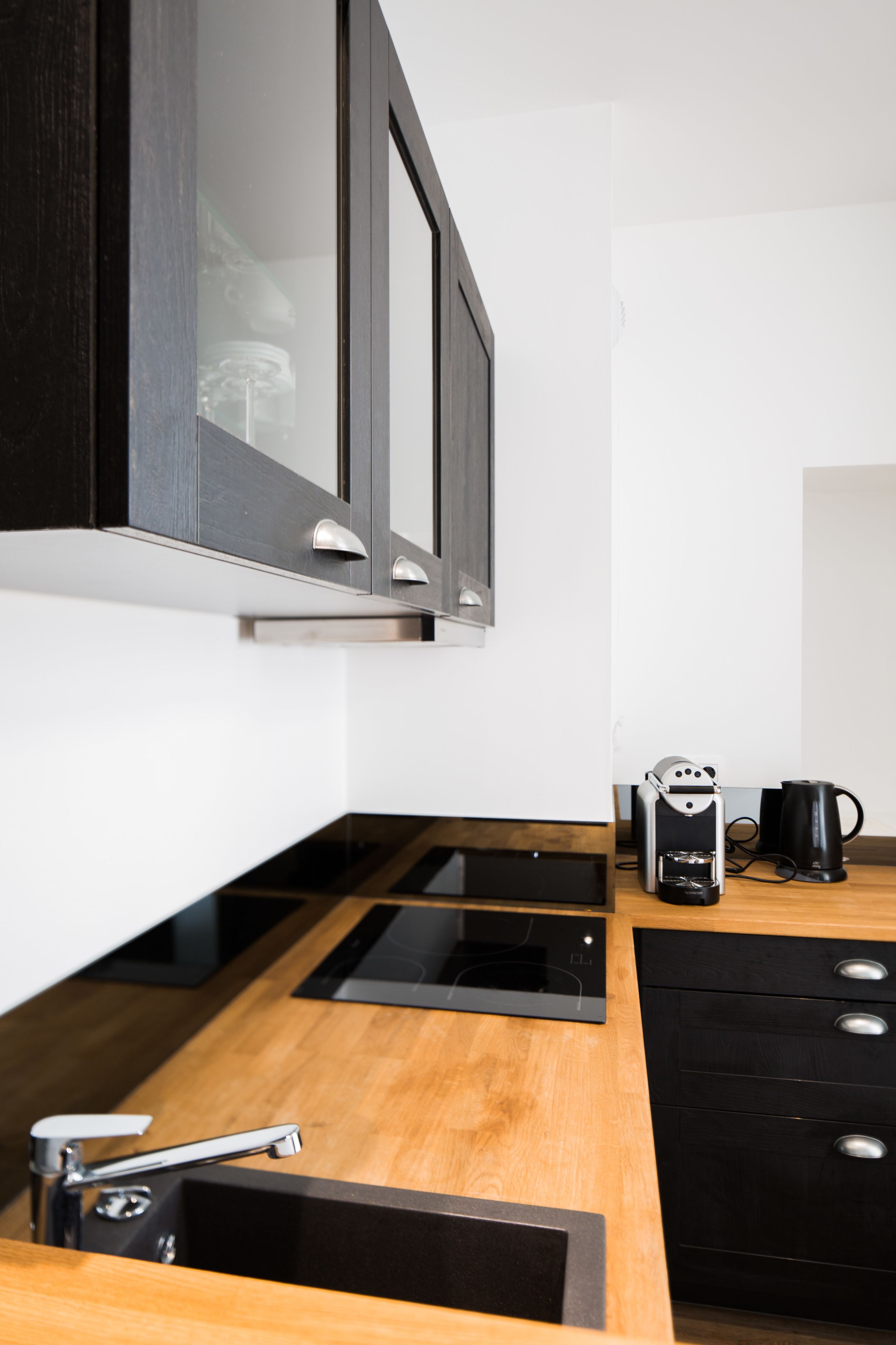 Eine moderne Küche mit Einbauofen, Kaffeemaschine und Wasserkocher auf der Arbeitsfläche.