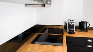 Eine moderne Küche mit Einbauofen, Kaffeemaschine und Wasserkocher auf der Arbeitsfläche.