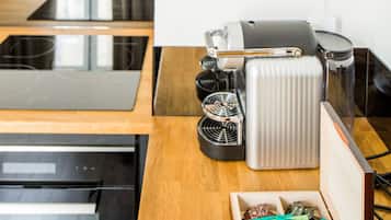 Et køkken med kaffemaskine, elkedel og en pakke kaffekapsler.