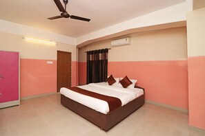 Relax in this serene space with a large bed, ceiling fan, and air conditioning unit.