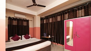 A bedroom with a bed, a desk, a wardrobe, and a ceiling fan. - OYO 4979 Prabha Palace Lodge (Guwahati)