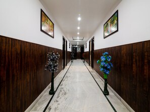 A hallway with wooden paneling, marble flooring, and framed artwork on the walls.