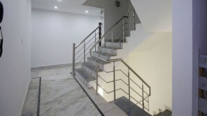 Un escalier moderne avec des rampes en métal et des marches en marbre, menant à l’étage supérieur.