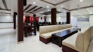 Un vaste espace intérieur comprenant un long canapé beige, des tables en bois foncé et un ventilateur de plafond.