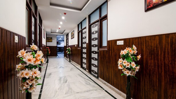 Un couloir d’hôtel avec un sol en marbre, des boiseries et des décorations florales.