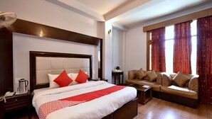 Une chambre d’hôtel avec un grand lit, un canapé, une petite table et une fenêtre avec des rideaux.