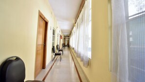 Un couloir avec des portes, des chaises et des fenêtres avec des rideaux.
