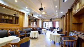 Un hall d’hôtel spacieux, doté de sièges en cuir, de tables et d’un lustre.