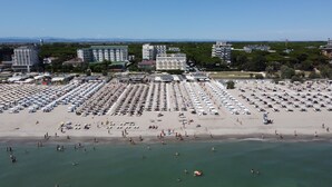 Una playa con numerosos sombrillas y tumbonas, una orilla arenosa y una vista despejada del mar.