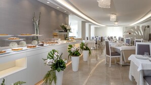 Un comedor moderno con una barra alargada que exhibe pasteles y una lámpara de araña.