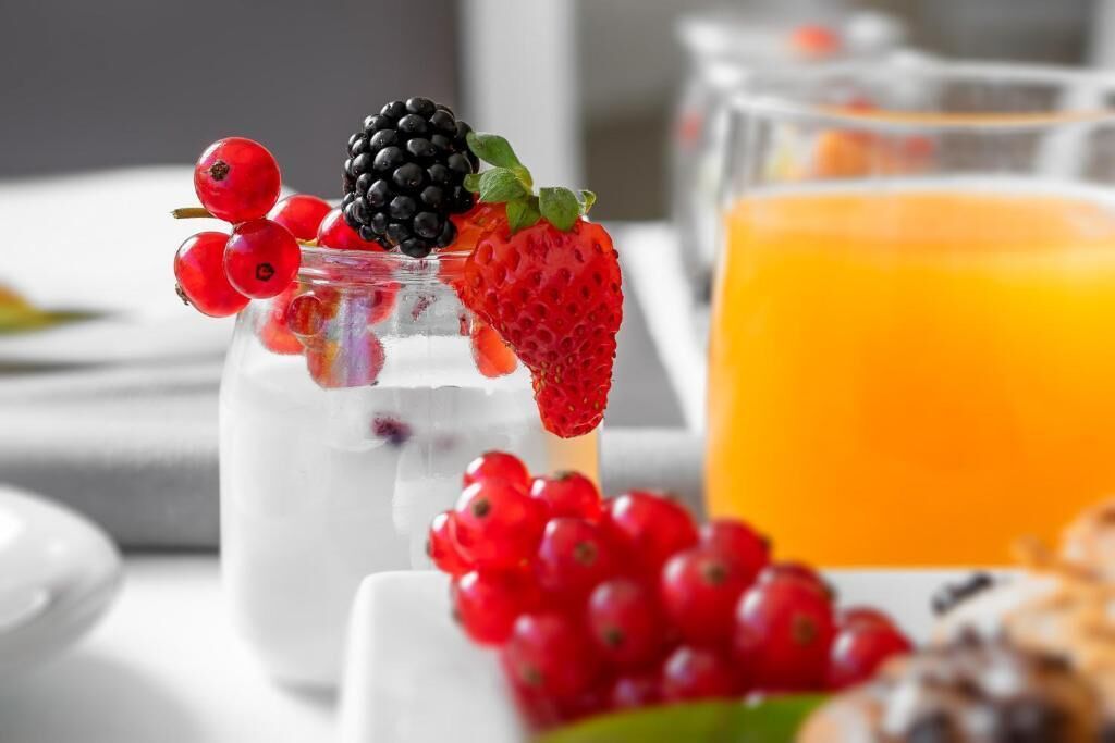 Ein Glas Joghurt mit Beeren und ein Glas Orangensaft auf einem Tisch.
