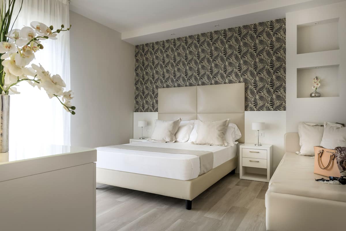 A modern bedroom with a large bed, bedside tables, a nightstand, a dresser, and a vanity with a mirror.