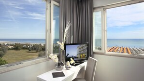 Una habitación con escritorio, computadora y vista a la playa y al mar.