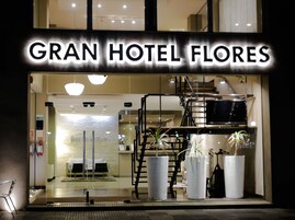 Exterior del Gran Hotel Flores, con un diseño moderno que incluye una escalera y plantas en macetas.
