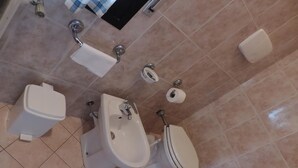 Een badkamer met een hygiëneschuimer, toilet en wastafel.