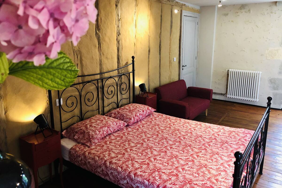 A bedroom with a bed, a chair, a radiator, and a door.