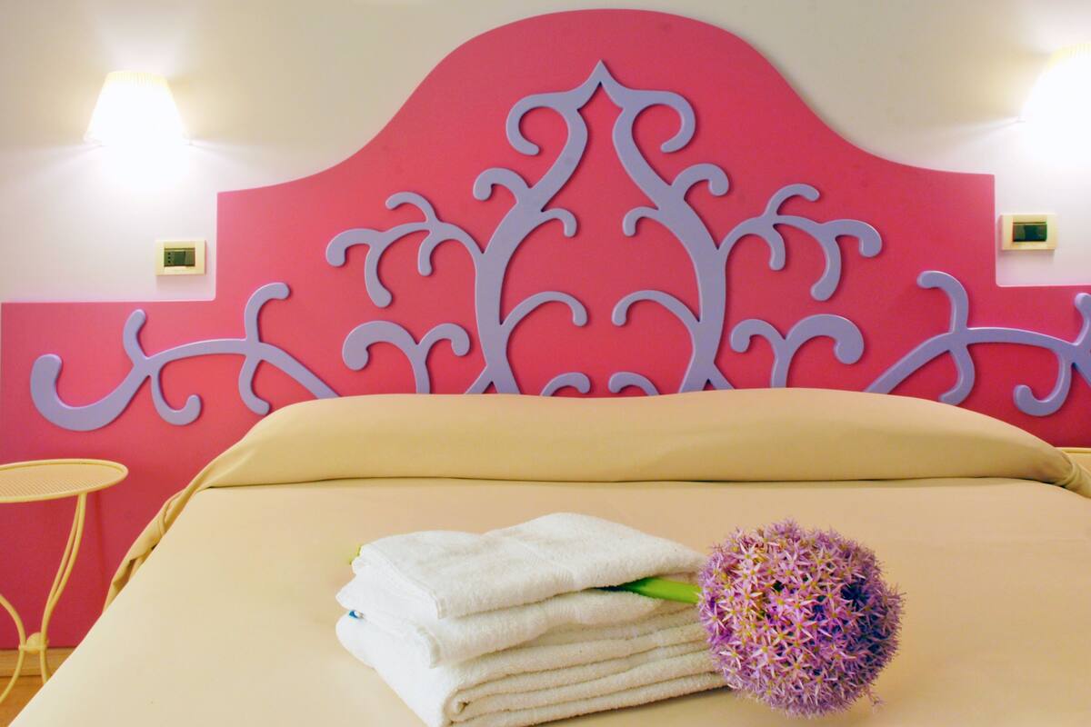 Une chambre d’hôtel avec un grand lit, deux tables de chevet et une tête de lit décorative.