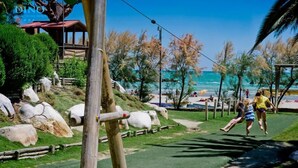 Un parc doté d’une structure en bois, d’un sentier et, au loin, d’une plage.