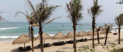 Een privéstrand, ligstoelen aan het strand, parasols, strandlakens