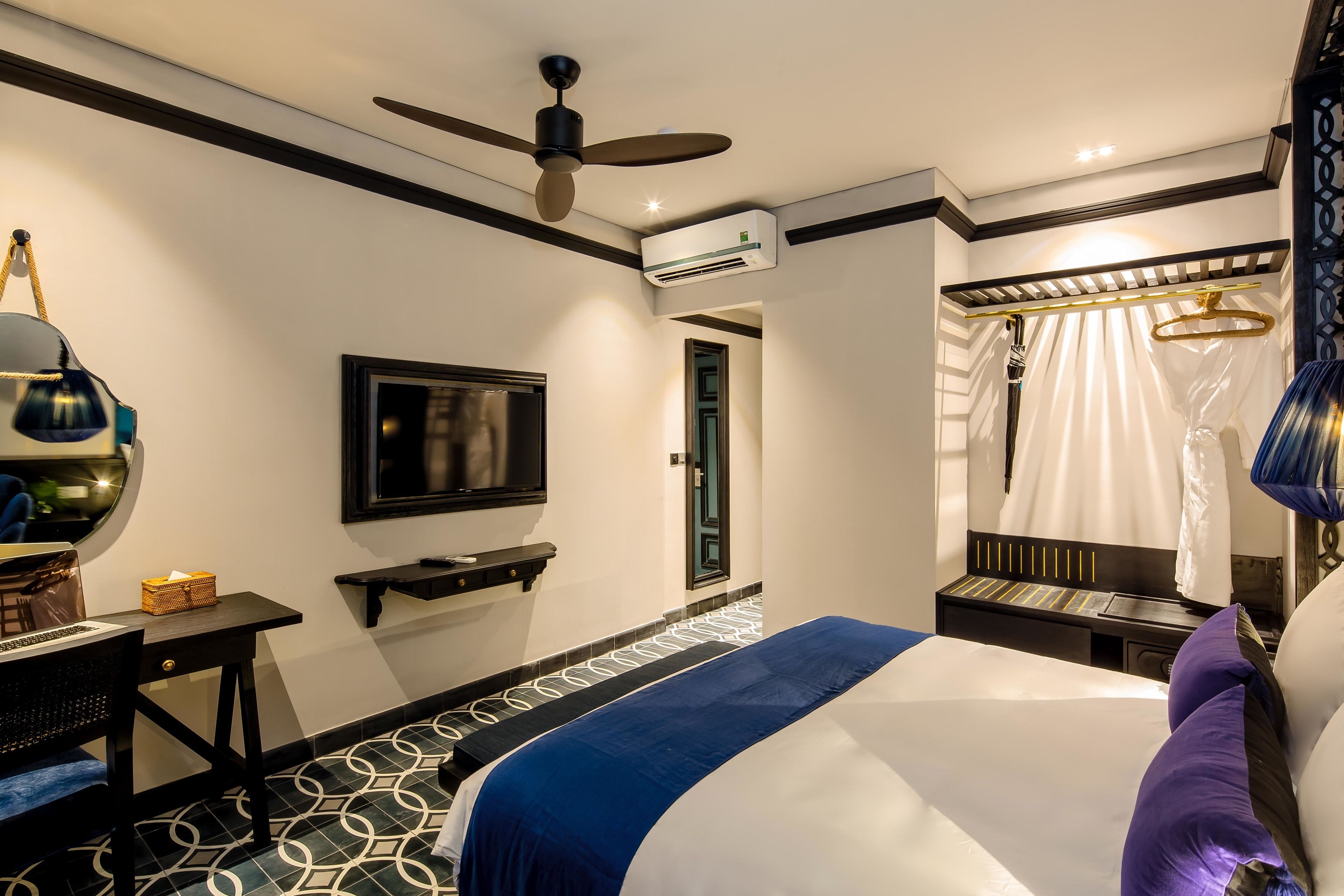 Une chambre d’hôtel équipée d’un lit, d’un bureau, d’une télévision et d’un appareil de climatisation.