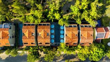 A rooftop pool area with multiple swimming pools, surrounded by trees and buildings.
